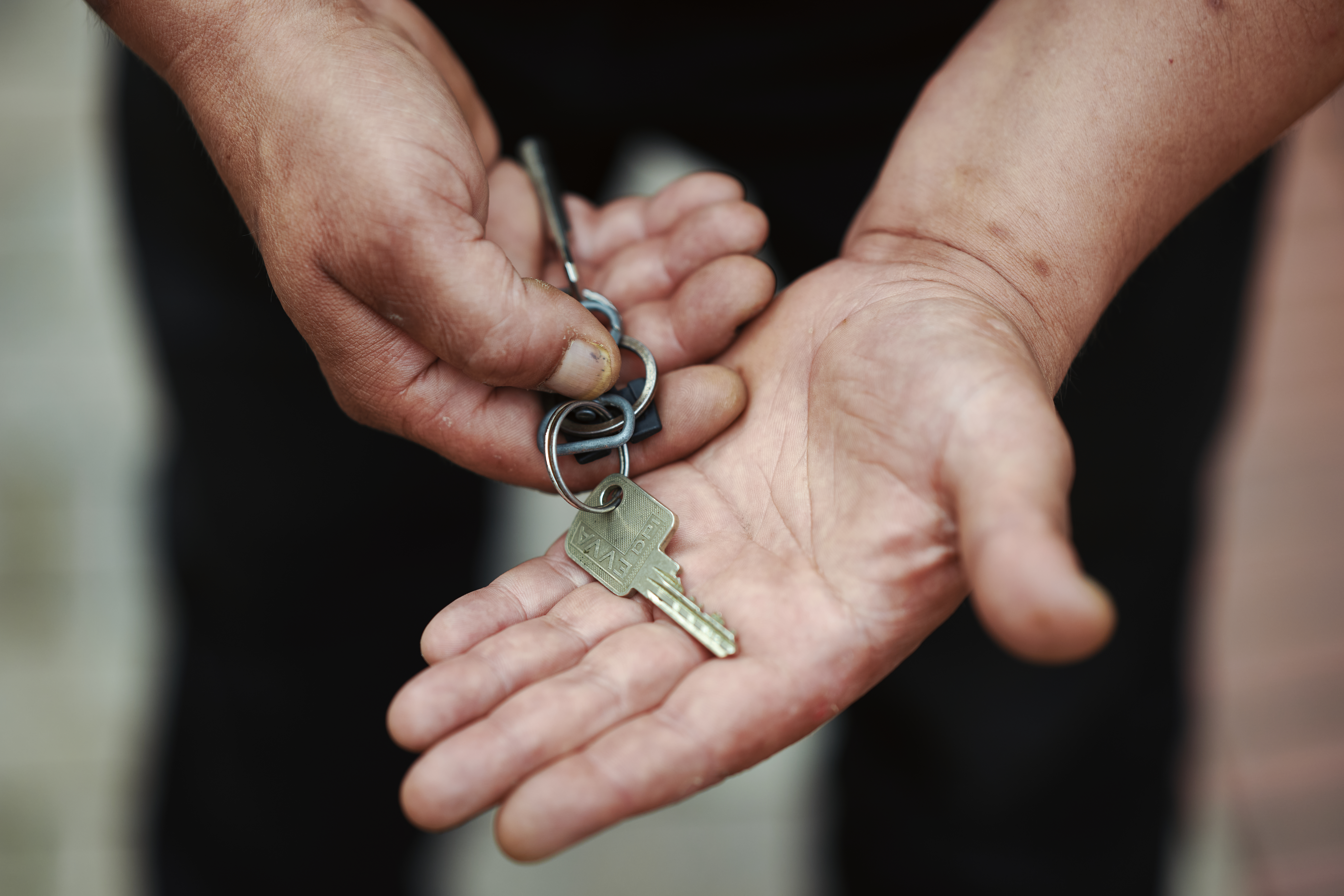 Eine Hand legt einen Schlüssel in eine andere Hand.