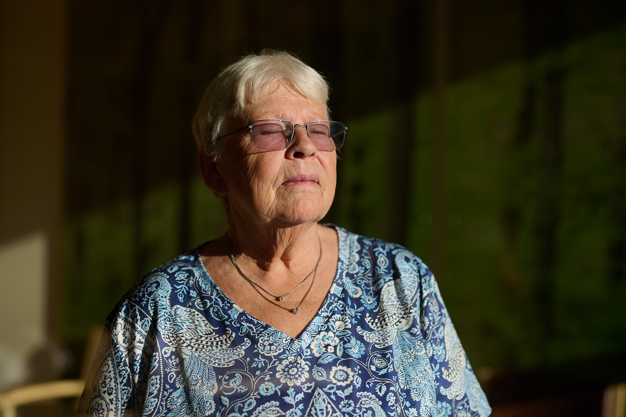 Eine Frau schaut mit geschlossenen Augen ins Licht