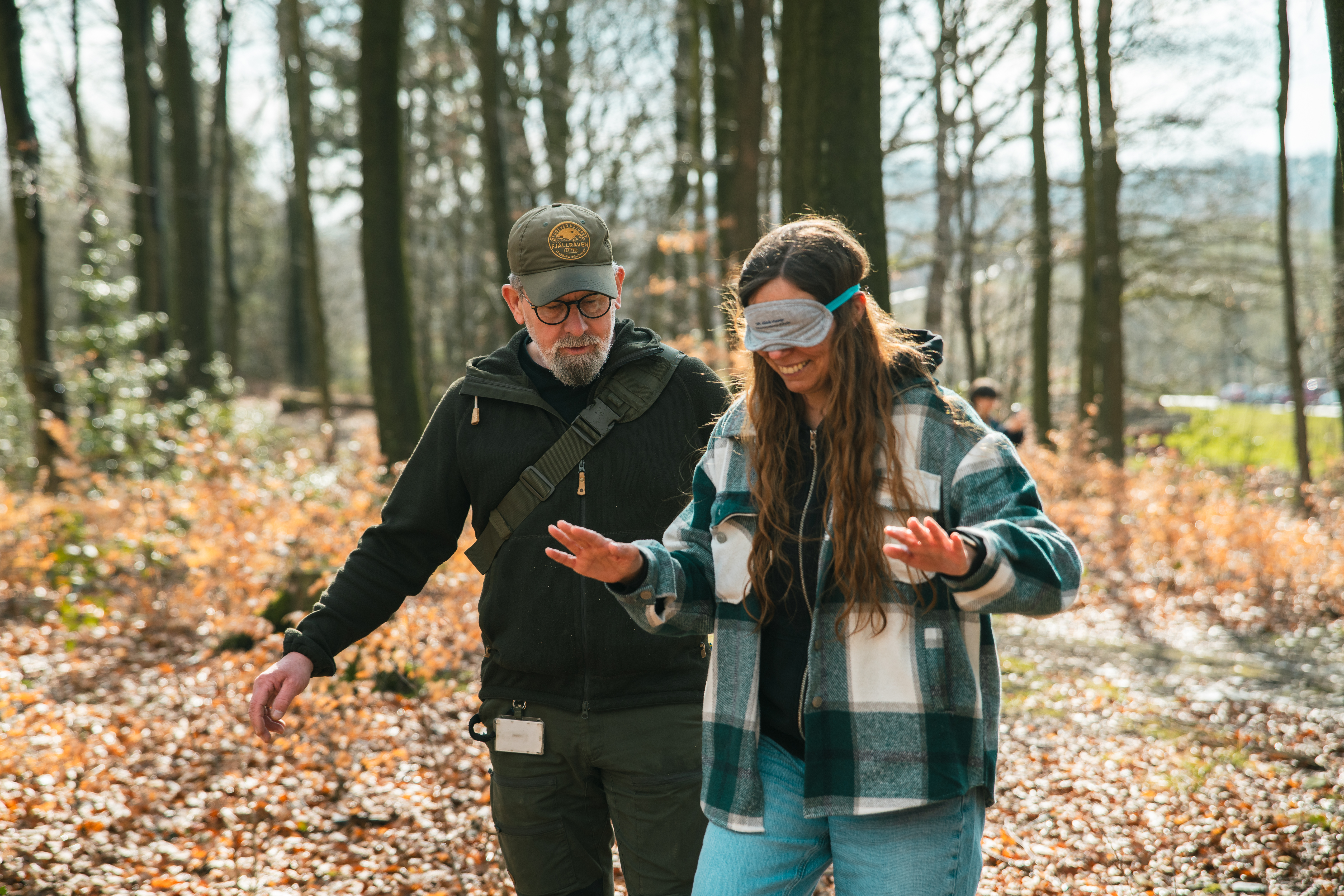 Eine Frau geht mit verbundenen Augen durch den Wald.