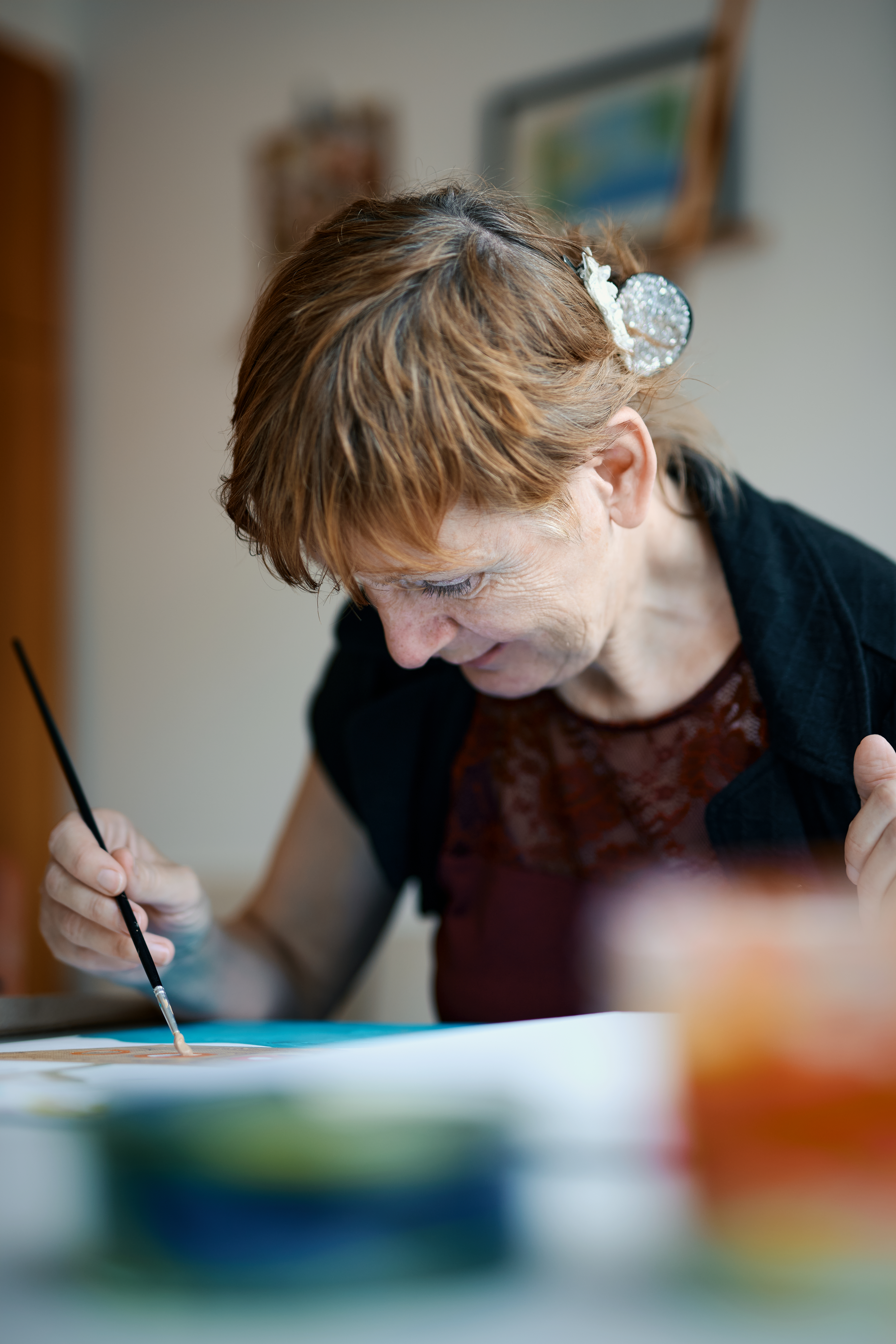 Ursula Rehmet sitzt am Tisch und malt.