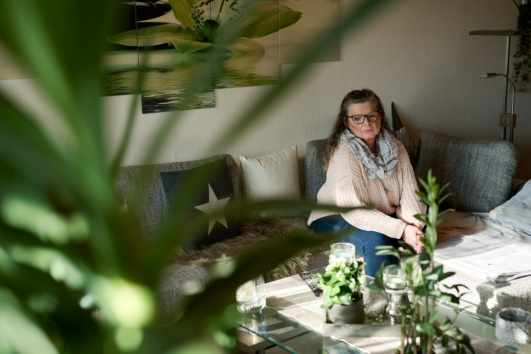 Eine Frau sitzt nachdenklich im Wohnzimmer.
