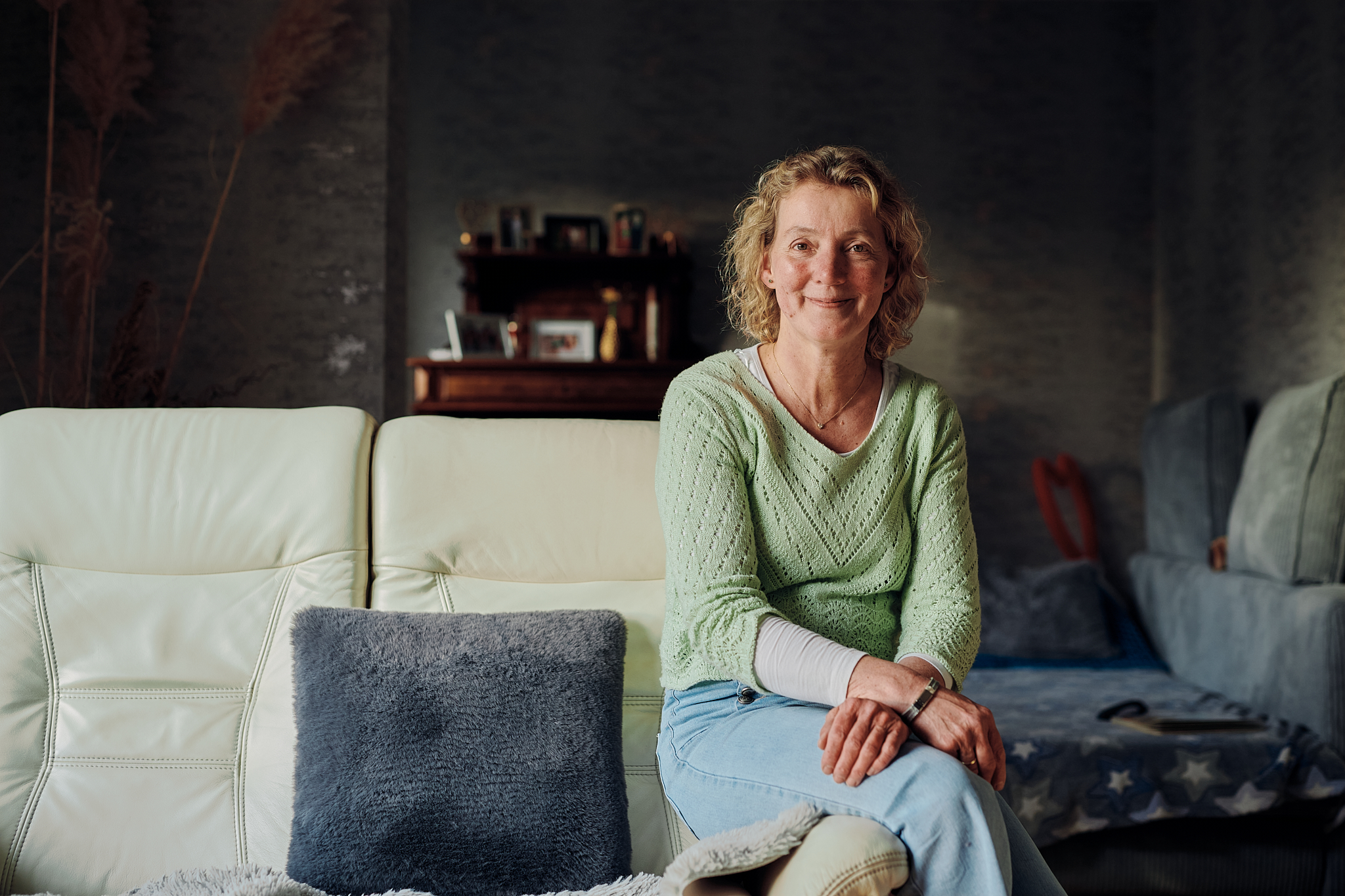 Eine Frau sitzt auf einer Sofa-Lehne und lächelt in die Kamera.https://www2.lwl.org/de/LWL/portal/lwl-storys/2026/steppke/?edit&language=de#