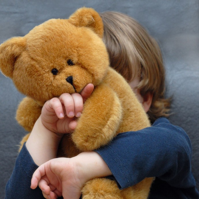 Ein Kind kuschelt mit einem Teddy. (vergrößerte Bildansicht wird geöffnet)