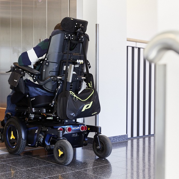 Ein Mann fährt mit seinem elektrischen Rollstuhl in einen Aufzug. (vergrößerte Bildansicht wird geöffnet)