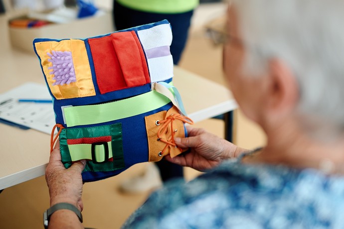 Eine Frau hält ein buntes Nestelkissen.
