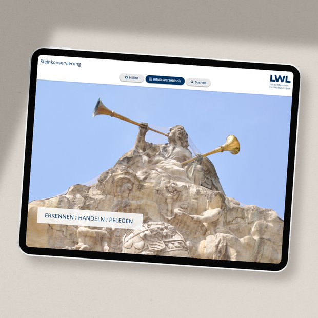 Tablet, auf dem die Website des Steinkonservierungsleitfadens aufgerufen ist: Sandsteinzierwerk mit goldenen Posaunen vor blauem Himmel Tablet, auf dem die Website des Steinkonservierungsleitfadens aufgerufen ist: Sandsteinzierwerk mit goldenen Posaunen vor blauem Himmel