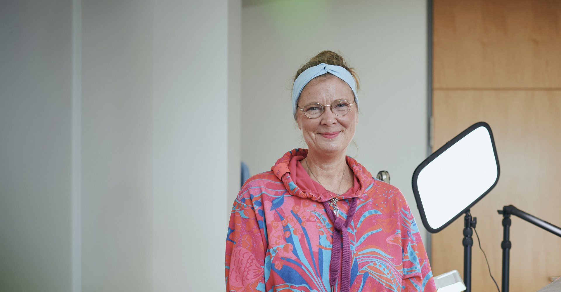 Maike Kloss steht neben einer hellen Arbeitsleuchte und lächelt in die Kamera