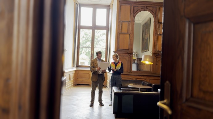 Mann und Frau im Gespräch über einem Plan, in Mitten eines Raumes.