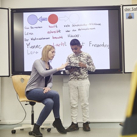 Lehrerin und Schüler beim Unterricht vor einer Tafel