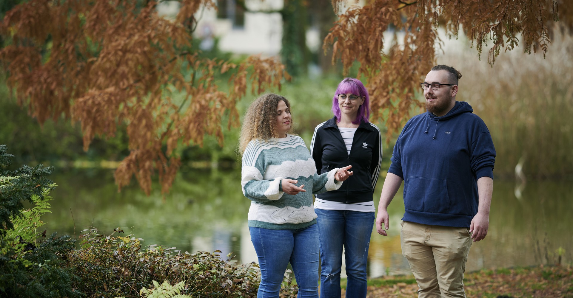 Drei Menschen stehen in der Natur und machen Atemübungen
