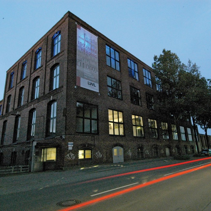Ein altes Industriegebäude aus Stein mit vielen Fenstern von außen und bei Nacht (öffnet vergrößerte Bildansicht)