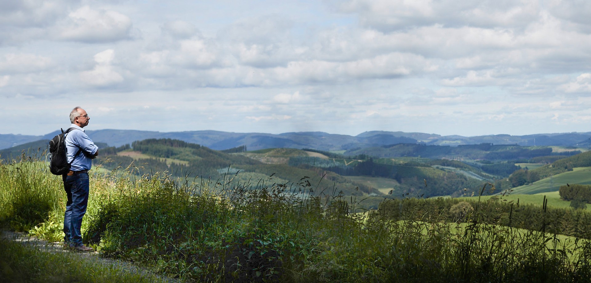 LWL-Direktor Matthias Löb mit Blick auf eine hügelige und teilweise bewaldete Landschaft
