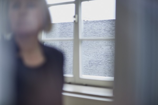 Das Foto zeigt eine Frau die sich von einem Fenster wegdreht.
