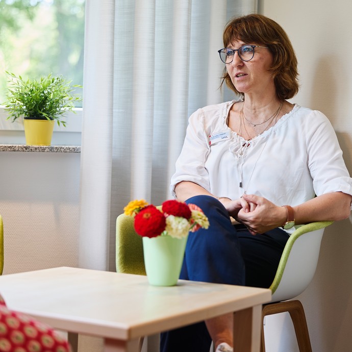 Eine Frau sitzt auf einem Stuhl und redet. (vergrößerte Bildansicht wird geöffnet)