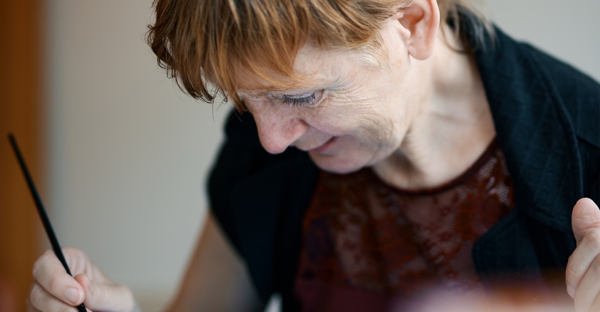 Ursula Rehmet sitzt am Tisch und malt.