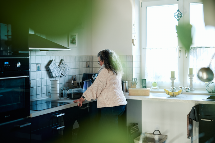 Eine Frau steht einsam in der Küche.