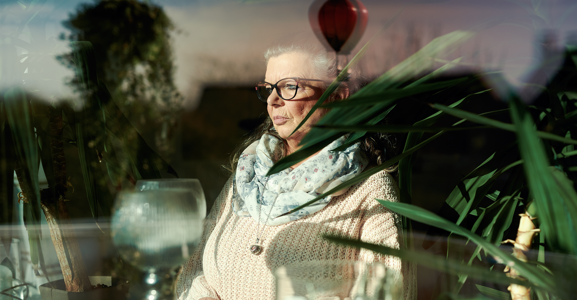 Ein Frau hält ein Glas Tee in den Händen und schaut aus dem Fenster.
