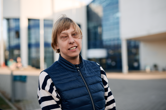 Sabrina Führer in blauer Weste lächelt in die Kamera, im Hintergrund Glasfassade des Hochschul-Gebäudes