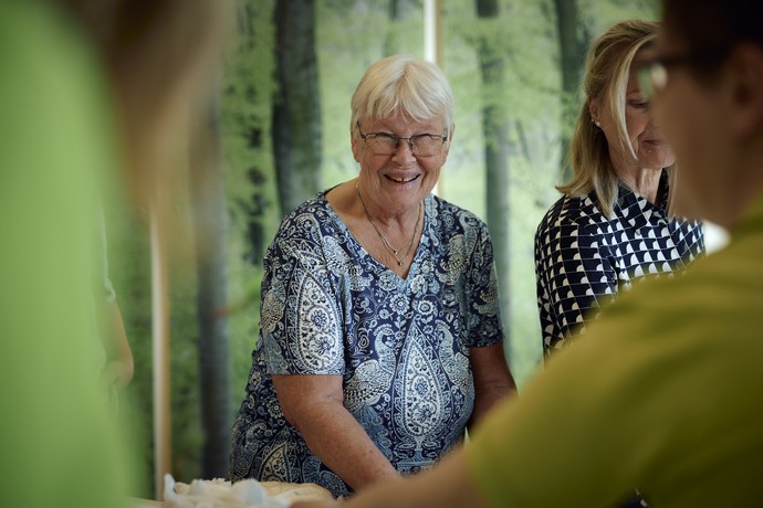 Frau steht zwischen Kursteilnehmenden und lächelt