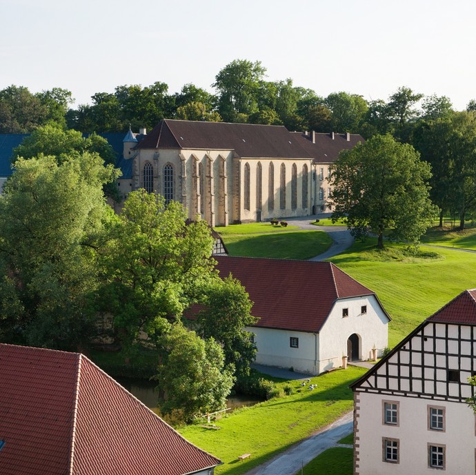 Das Kloster Dalheim von außen und von oben. Um das Hauptgebäude stehen einige alte Fachwerkhäuser. Das Kloster ist von Wiese und Bäumen umgeben. (vergrößerte Bildansicht wird geöffnet)