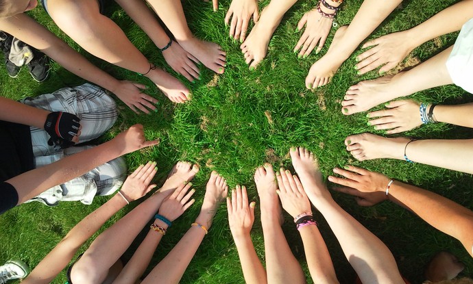 Viele Hände und Füße bilden auf einer Wiese einen Kreis Viele Hände und Füße bilden auf einer Wiese einen Kreis