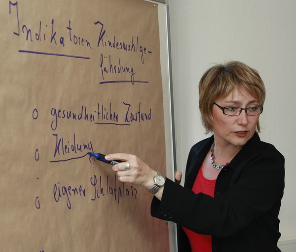 Eine Lehrerin schreibt etwas an eine Schautafel.