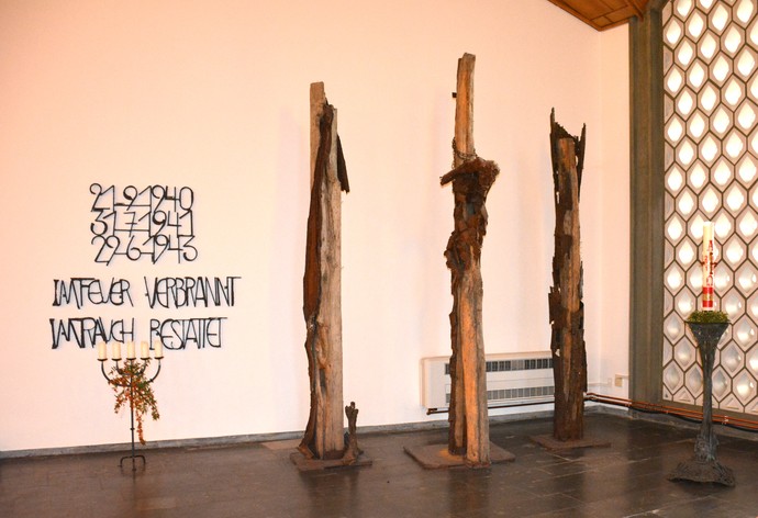 Mahnmal im Innenraum der Kirche. Daneben in großen Buchstaben die Worte "IM FEUER VERBRANNT IM RAUCH BESTATTET"