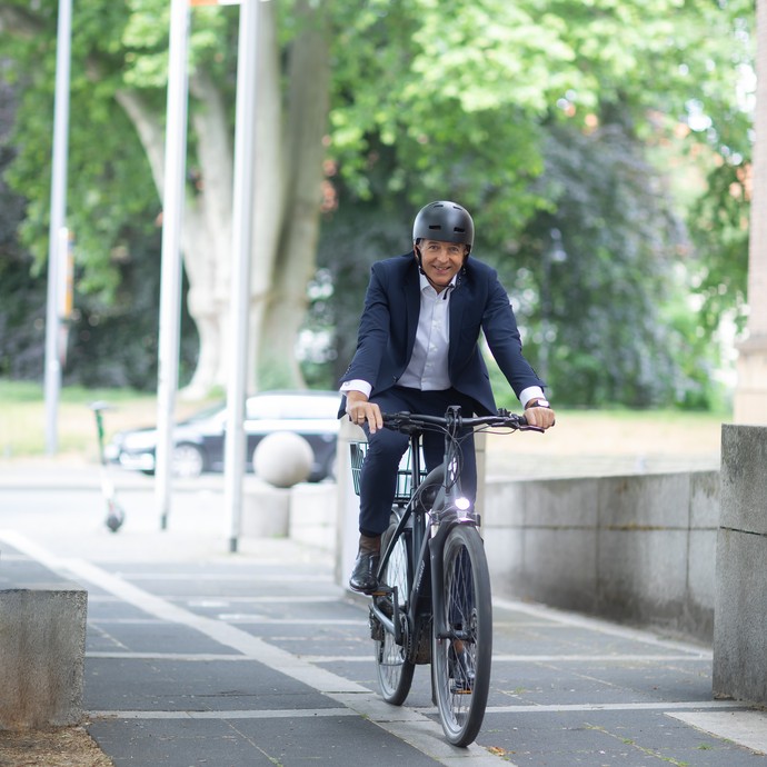Dr. Georg Lunemann auf einem Fahrrad fahrend vor dem Eingang des Landeshauses. (öffnet vergrößerte Bildansicht)