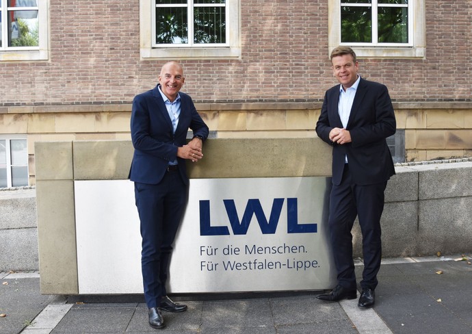 Matthias Heidmeier und Dr. Georg Lunemann vor dem LWL-Logo